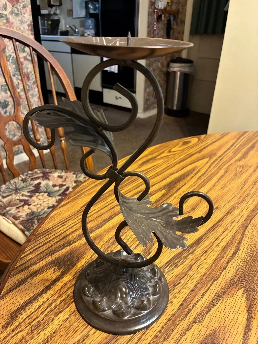 vintage-style brown cast iron pillar candle holder features an ornate leaf